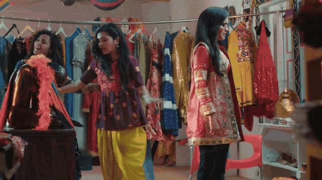 three women are standing in front of a display of clothes