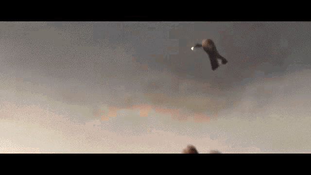 a bird is flying through a cloudy sky with a light in its beak