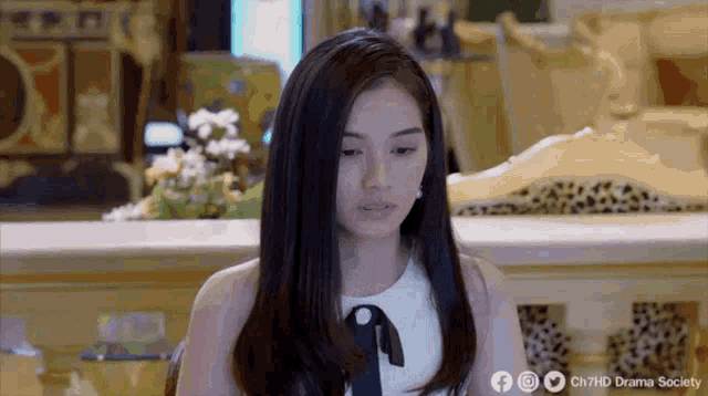 a woman with long black hair is sitting in a chair and looking at the camera .