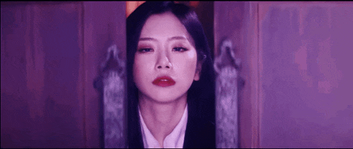 a close up of a woman 's face in a dark room with purple lights .