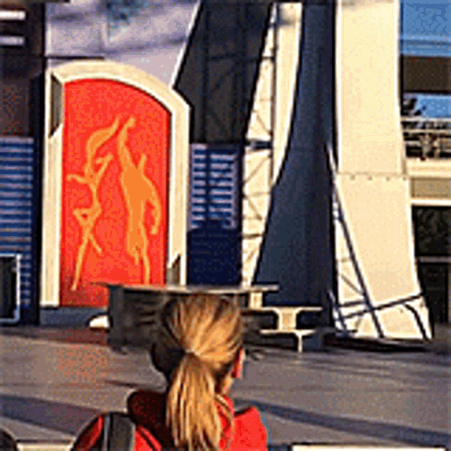 a woman wearing a graduation cap is sitting in front of a large building