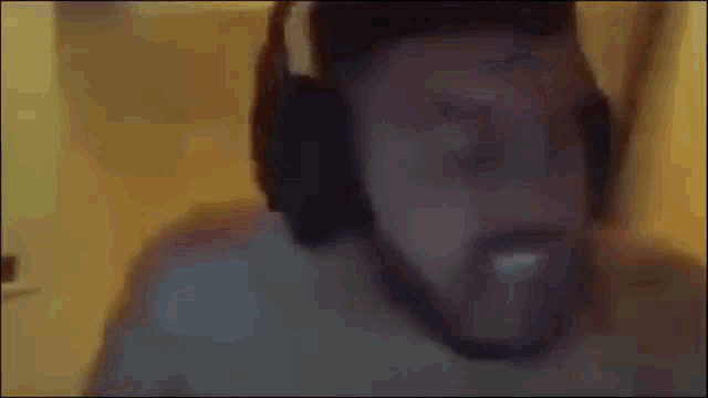 a man with a beard wearing headphones is making a funny face .
