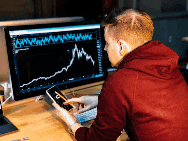 a man in a red hoodie is looking at a graph on his phone