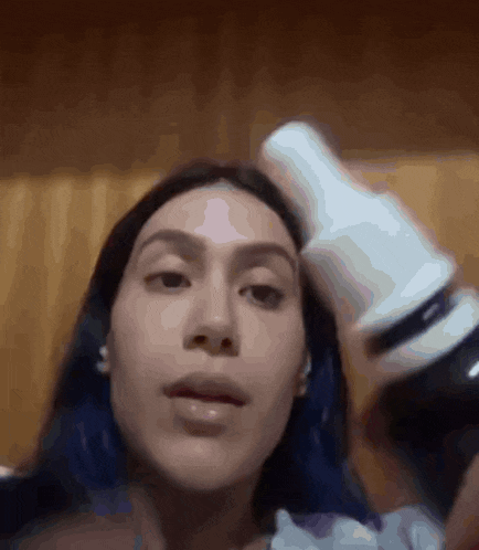 a woman with blue hair is holding a bottle in her hand