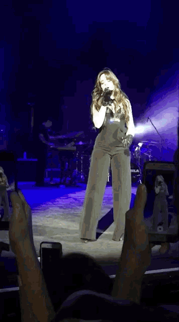 a person taking a picture of a woman singing on a stage