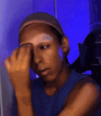 a person covering their face with their hand in front of a blue background