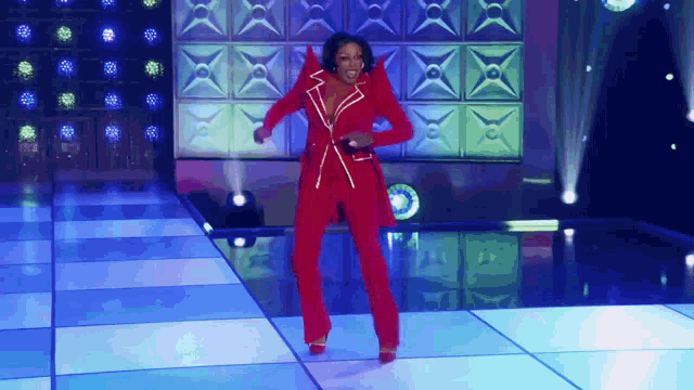 a woman in a red suit is standing on a dance floor