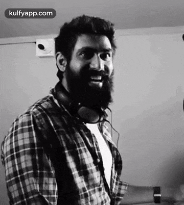 a black and white photo of a man with a beard wearing headphones and a plaid shirt .