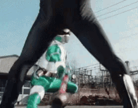 a man in a black suit is standing next to a green superhero in a green suit .