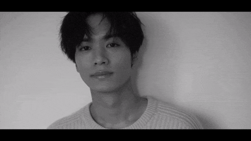 a black and white photo of a man wearing a white sweater