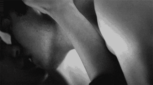 a black and white photo of a man and woman kissing each other .