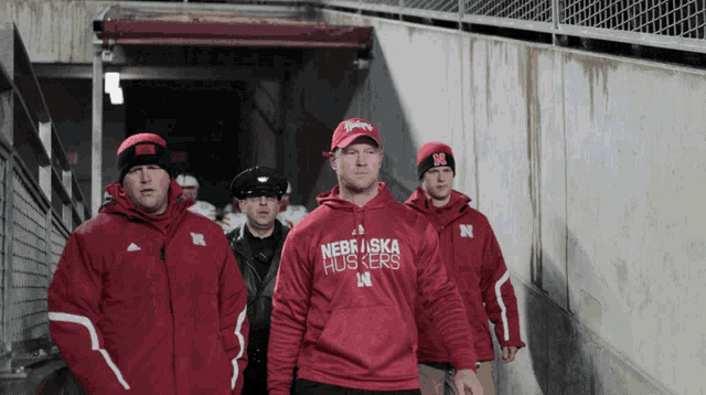 a man wearing a nebraska huskers sweatshirt walks down a staircase