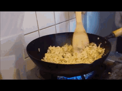 a wooden spoon is being used to stir food in a wok