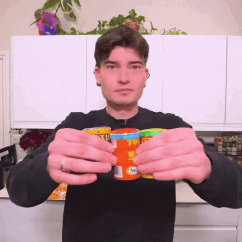 a man in a black sweater is holding a can of juice