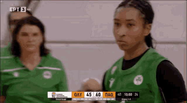 a female basketball player stands in front of a scoreboard that says oay 45 60 pao
