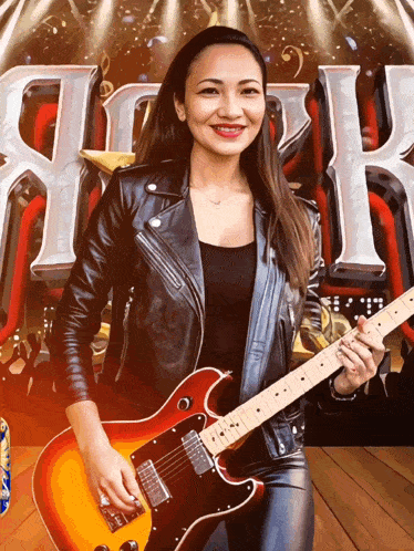 a woman in a leather jacket holding a guitar in front of a sign that says rock