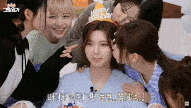 a girl wearing a happy birthday hat kisses another girl