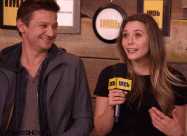 a man and a woman are standing next to each other and the woman is holding a microphone that says imdb on it