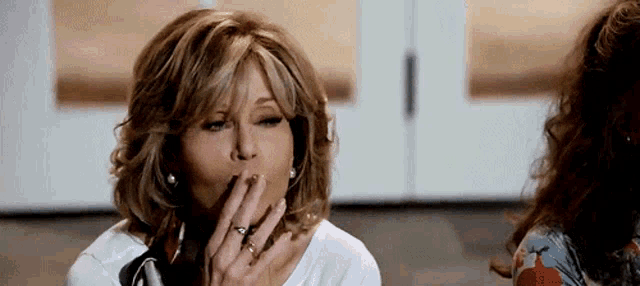 a woman with a ring on her finger is smoking a cigarette