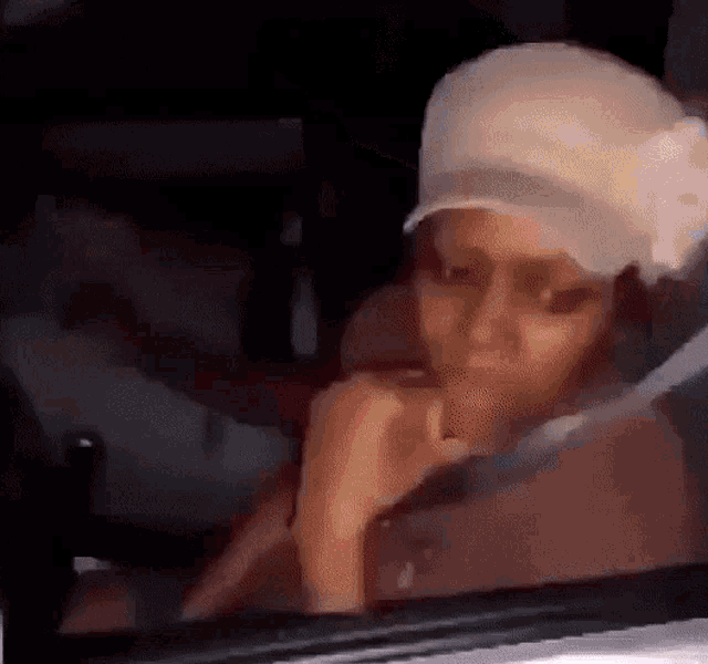 a woman wearing a baseball cap is sitting in a car .