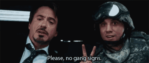 a man in a suit and tie is sitting next to a man in a military uniform and says please no gang signs .