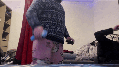 a person wearing hello kitty pajamas is holding a remote