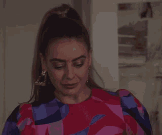 a woman with a ponytail wearing a colorful dress and earrings