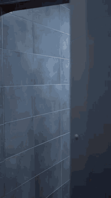 a shirtless man with a towel around his waist stands in a shower