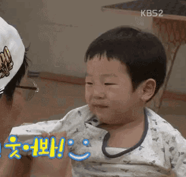 a little boy is being held by a man with kbs2 on the bottom right
