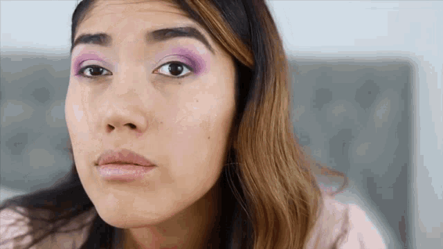 a close up of a woman 's face with purple eyeshadow on