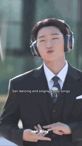 a man in a suit and tie is wearing headphones and singing kpop songs .