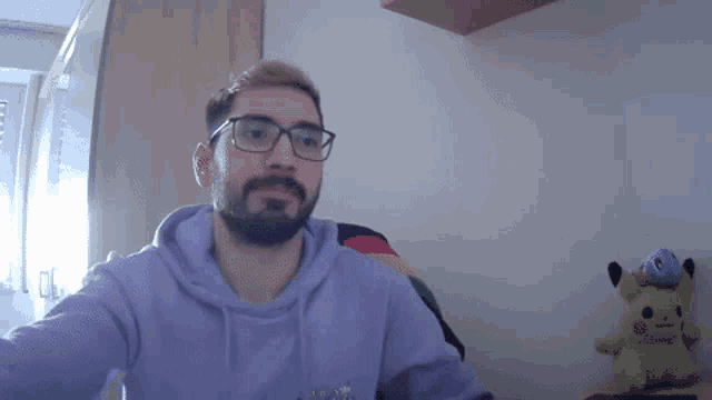 a man wearing glasses and a purple hoodie takes a selfie