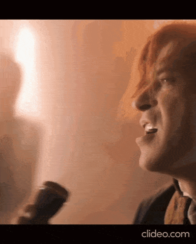 a close up of a man singing into a microphone