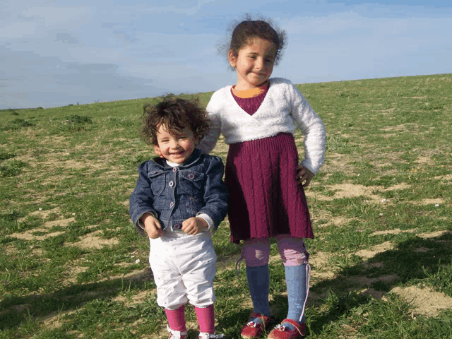 two little girls standing in a grassy field
