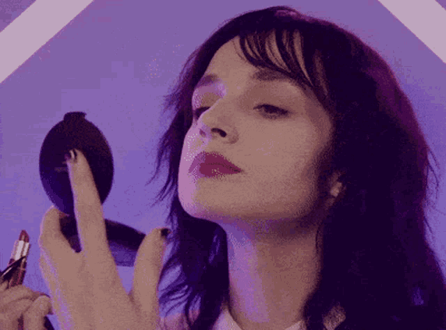 a woman is applying red lipstick to her lips