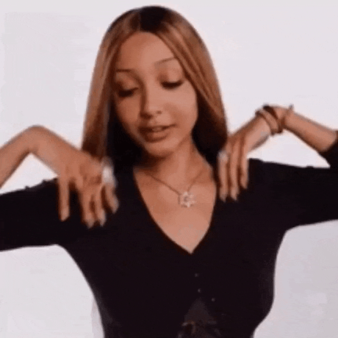 a woman wearing a black sweater and a necklace is stretching her arms out .