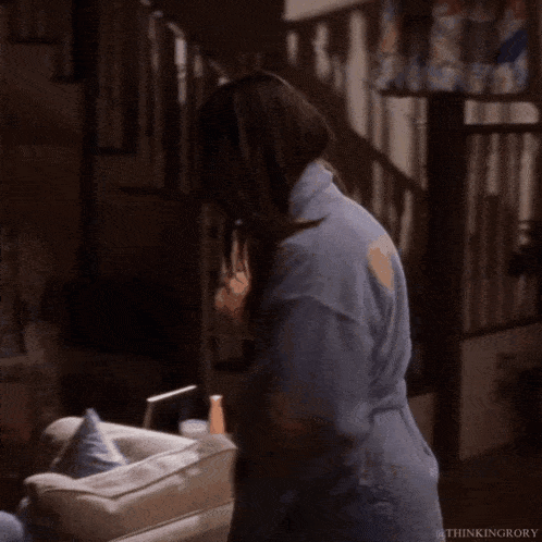 a woman in a blue robe is kneeling down in a living room with a lamp in the background