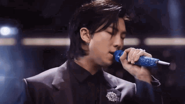 a man is singing into a blue microphone