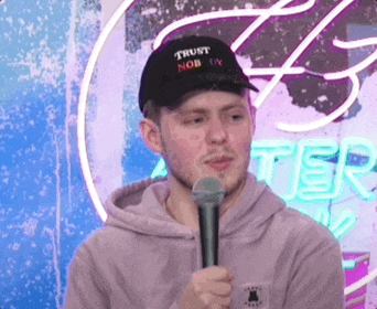 a man wearing a hat that says trust nob ux holds a microphone