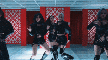 a group of women are dancing in a room with a red wall