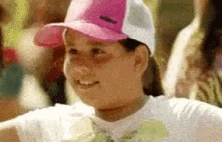 a girl wearing a pink hat and a white shirt is smiling