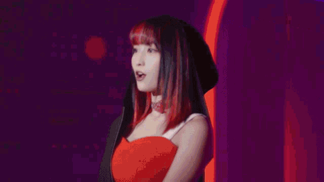 a woman with green hair is holding a pink object decorated with hearts and ribbons .