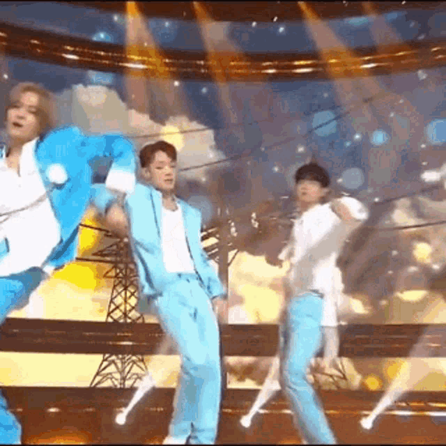 a group of men are dancing on a stage in front of a crowd .