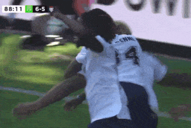 a soccer player with the number 14 on his back is hugging another player