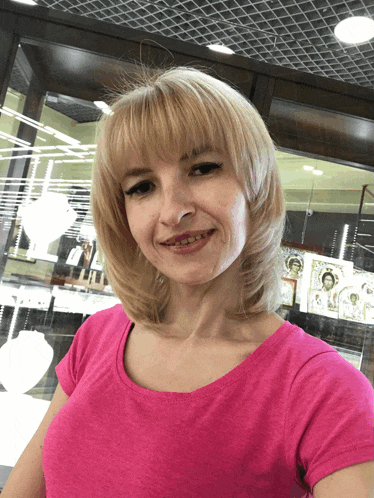 a woman in a pink shirt stands in front of a display of jewelry