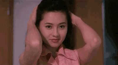 a young woman in a pink shirt is holding her hair with her hands .
