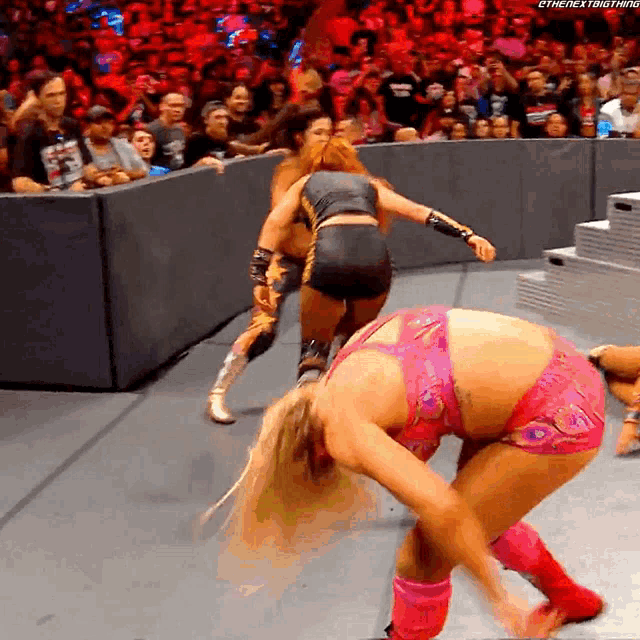 a woman in a pink outfit is kneeling down in front of a crowd while another woman stands behind her
