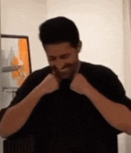 a man with a mustache is making a funny face while wearing a black shirt and tie .