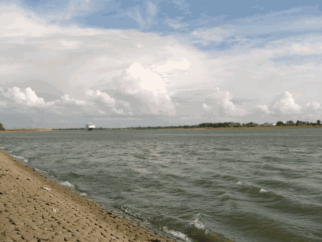 a large body of water with a boat in the distance and a cloudy sky