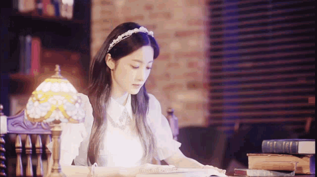 a girl is sitting at a table reading a book